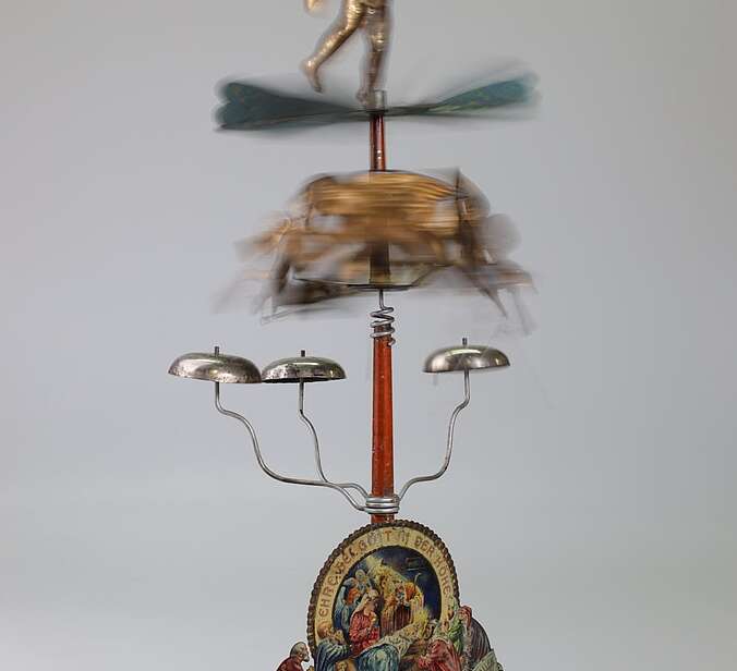 Ein aufgebautes Engelsgeläut aus Blech. Das Foto zeigt den Propeller und die Engel verschwommen, um Bewegung zu zeigen.